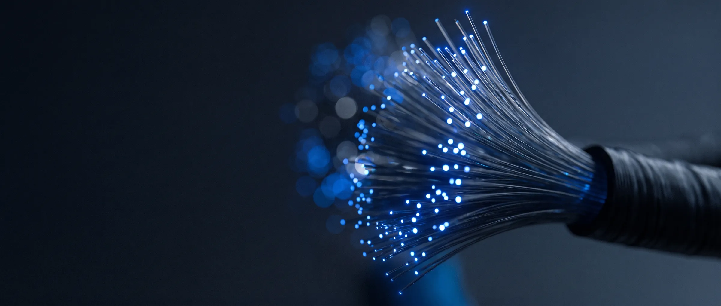 Feixe de fibra óptica se abrindo, com as pontas acesas em azul contra o escuro
